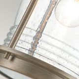 Close-up of a light fixture showcasing a clear, speckled glass shade containing an LED Edison-style bulb. The structure is enhanced by a metal rod and base with a burnished bronze finish, exuding elegance, while the textured glass with small bubbles adds charm similar to the Ashland Bay Outdoor 1 Light Large Wall Lantern - Burnished Bronze.
