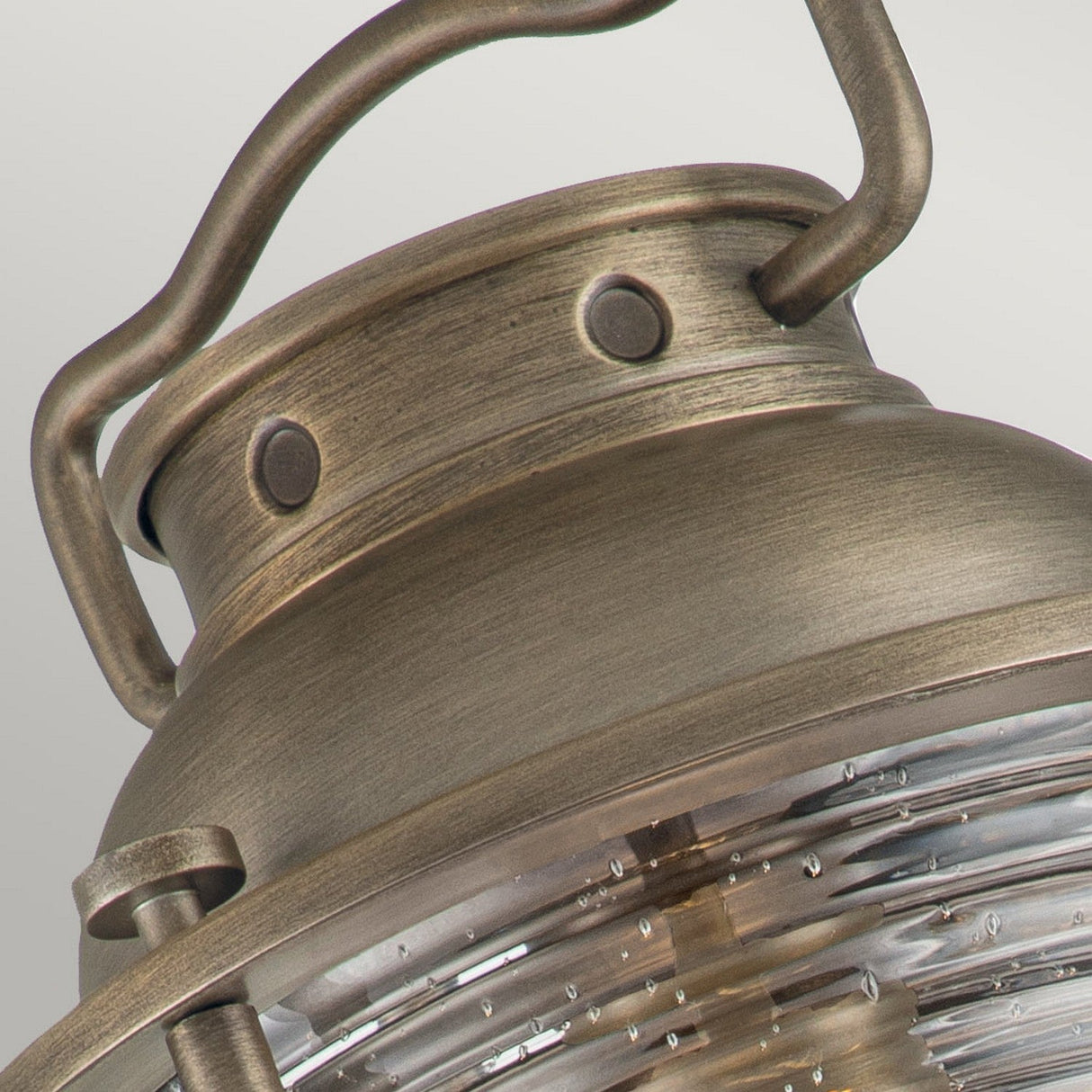 Close-up of the Ashland Bay Outdoor 1 Light Large Wall Lantern in Burnished Bronze, showcasing a vintage-style metal design with a textured glass cover. This lantern, fitted with an LED Edison-style bulb, features a handle and rivet details on its top section, set against a plain, neutral background.