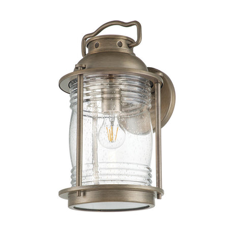 The Ashland Bay Outdoor 1 Light Large Wall Lantern - Burnished Bronze features a vintage-style design with a clear ribbed glass shade and an LED Edison-style bulb, elegantly mounted on a circular backplate.