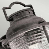 Close-up of the Ashland Bay Outdoor 1 Light Medium Wall Lantern, designed in a vintage style with a weathered zinc finish and seeded glass. It features a curved glass casing with small bubbles that enhance its rustic appearance. The lantern includes a handle at the top for easy carrying or hanging.