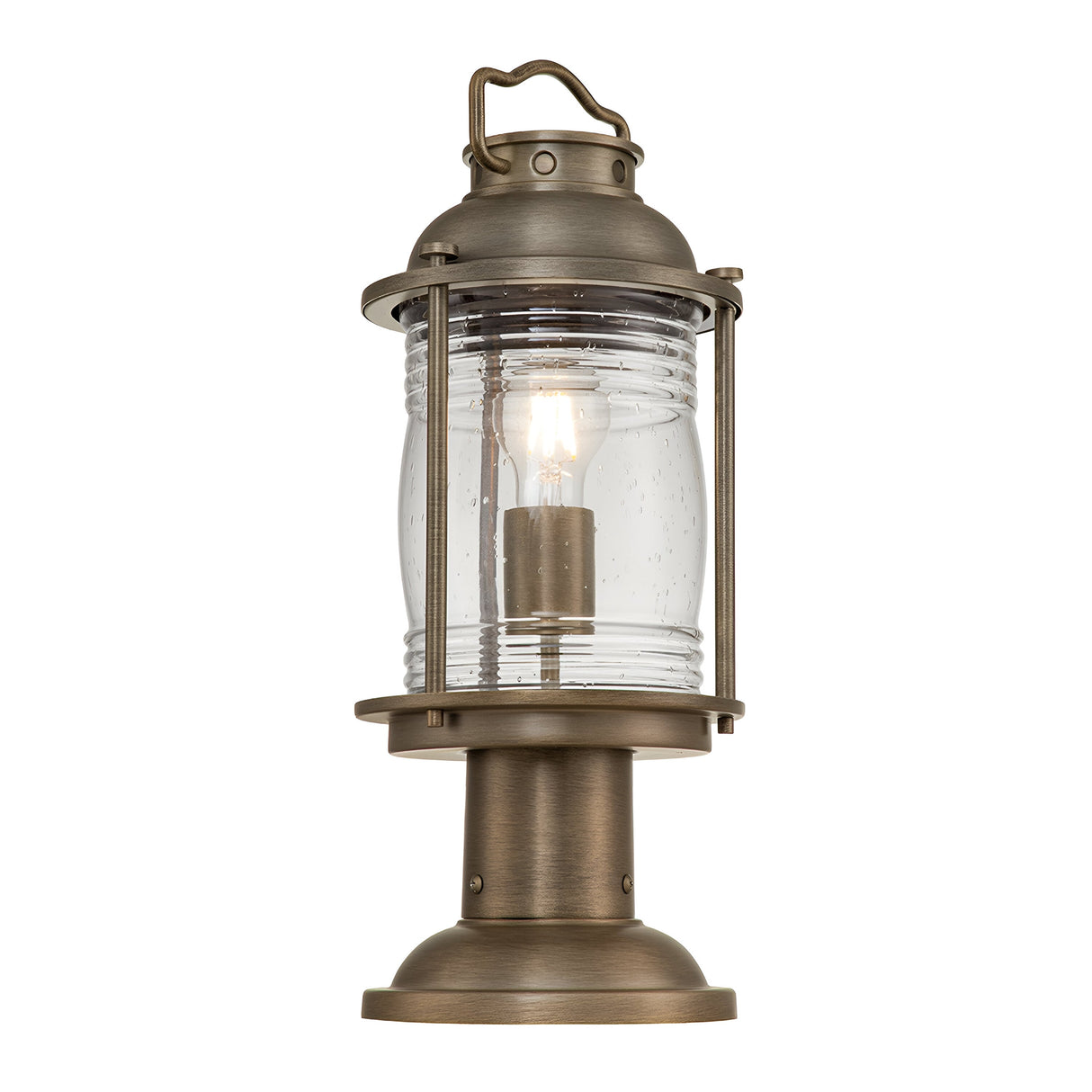 The Ashland Bay Outdoor 1 Light Medium Pedestal Lantern in burnished bronze features a vintage-style design with a clear glass enclosure that highlights a visible LED Edison bulb. It includes a handle on top and has a round base for stability, making it perfect for outdoor use.