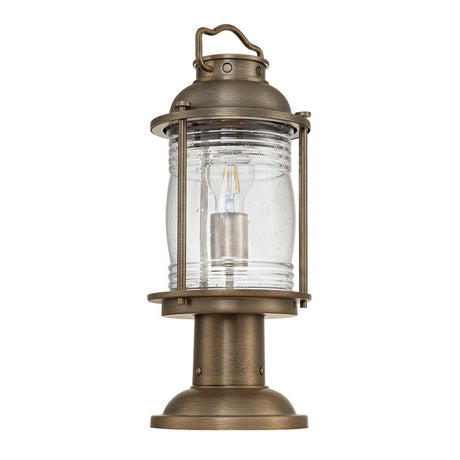 Introducing the Ashland Bay Outdoor 1 Light Medium Pedestal Lantern in burnished bronze, featuring a cylindrical glass enclosure accented with visible speckling and a robust base. Perfect for garden or porch illumination, this vintage-style lantern includes an LED Edison bulb to add a classic touch.