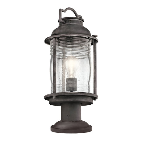 The Ashland Bay Outdoor 1 Light Medium Pedestal Lantern in a weathered zinc finish offers a vintage look with its clear, textured glass shade that houses an LED Edison-style bulb and is mounted on a cylindrical base.
