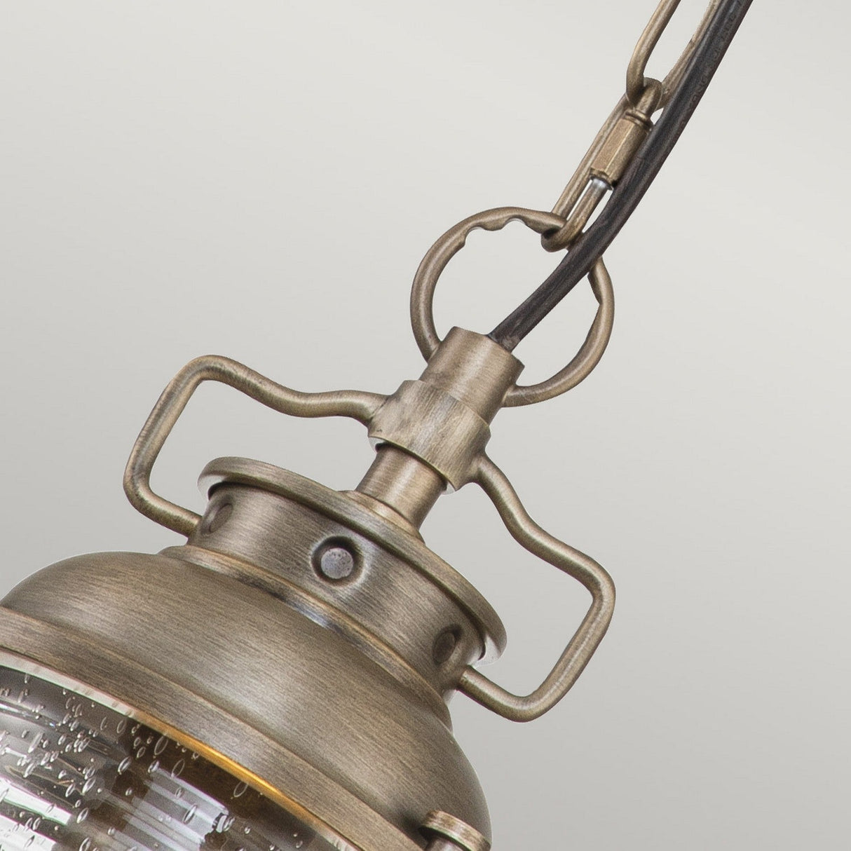 Capture the charm of an outdoor colonial-style lantern with a close-up of the Ashland Bay Outdoor 1 Light Small Chain Lantern in Burnished Bronze. Its vintage-style design showcases a textured glass enclosure, curved handle, and chain, adding rustic elegance to any space.