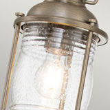Close-up of the Ashland Bay Outdoor 1 Light Small Chain Lantern featuring a clear, textured glass cover surrounding a glowing light bulb. This vintage-style lantern displays a colonial design with a brass frame in burnished bronze, radiating classic rustic charm.