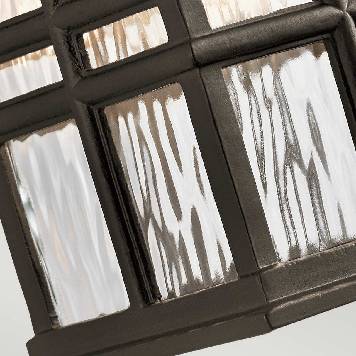 Close-up of the Beacon Square Outdoor 1 Light Small Wall Lantern in bronze, showcasing textured glass panels set in a dark metal frame. The wavy glass pattern enhances the grid design, making it ideal for elegant outdoor lighting.