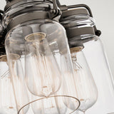 A close-up of the Brinley 6 Light Pendant - Bronze, displaying black metal and glass shades encasing vintage-style Edison bulbs, highlights the intricate filaments and industrial design.