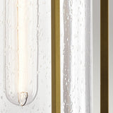 A close-up of the Camillo Outdoor 1 Light Medium Wall Lantern in Natural Brass showcasing clear seeded glass adorned with water droplets and bordered by vertical golden lines. The natural brass accents combined with the gentle light filtering through its slightly transparent surface offer a warm and elegant ambiance.