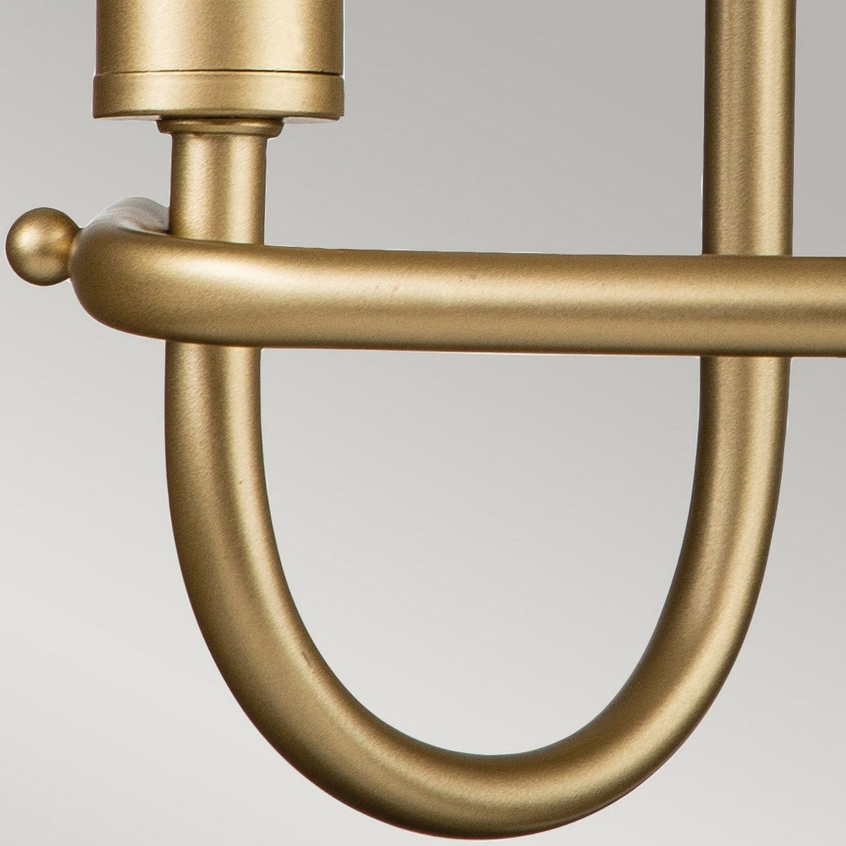 Close-up of a Capitol Hill 2 Light Wall Light in natural brass with a smooth, curved design set against a neutral gray background, this elegant fixture reflects the sophistication found in home lighting.