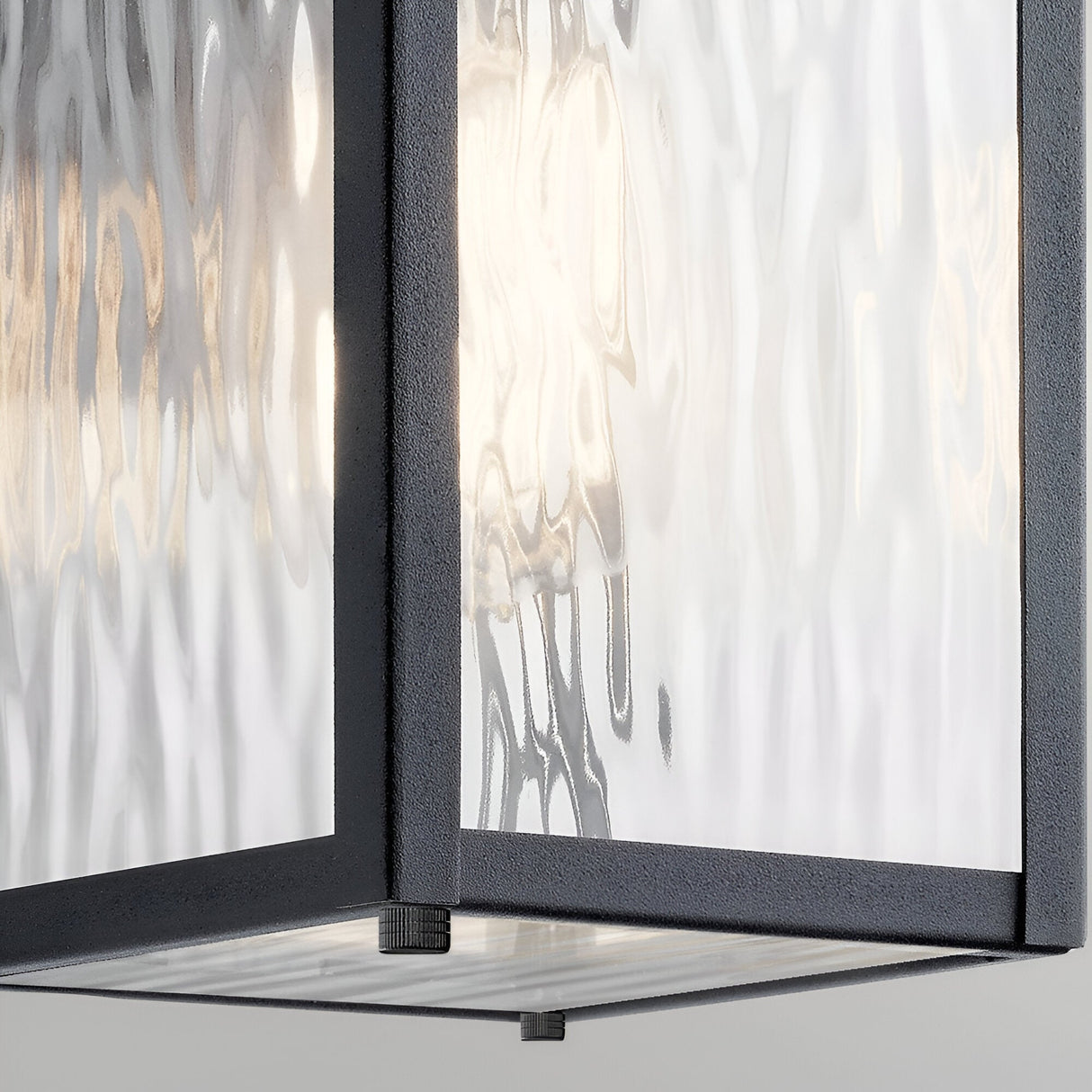Close-up of the Cappanna 1 Light Outdoor Small Wall Lantern in textured black, featuring clear waterfall glass panels with a softly glowing light—ideal for stylish outdoor lighting.