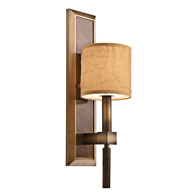 The Celestial 1 Light Wall Light in bronze boasts a rectangular backplate complemented by a textured, cylindrical beige shade. Its contemporary design is enhanced with optical crystal spheres, creating a soft, warm glow for a celestial ambiance.