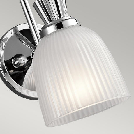Close-up of the Cora 1 Light Wall Light in polished chrome, boasting an IP44 rating and a frosted glass shade. The light gently illuminates the rippled glass surface.