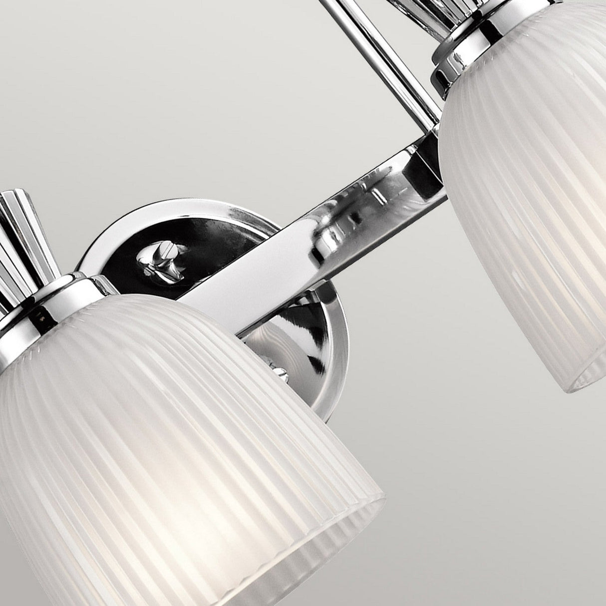Close-up of the Cora 2 Light Wall Light, featuring a polished chrome base and two white, ribbed glass shades. This sleek and contemporary LED-compatible design is perfect for bathroom lighting or enhancing any interior decor.