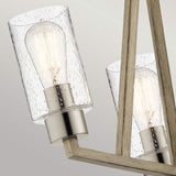 Up-close view of the Deryn 3 Light Chandelier, featuring modern light fixtures with clear seeded glass shades and exposed filament bulbs, set on brushed metal bases. The chandelier is mounted against an antique grey background.