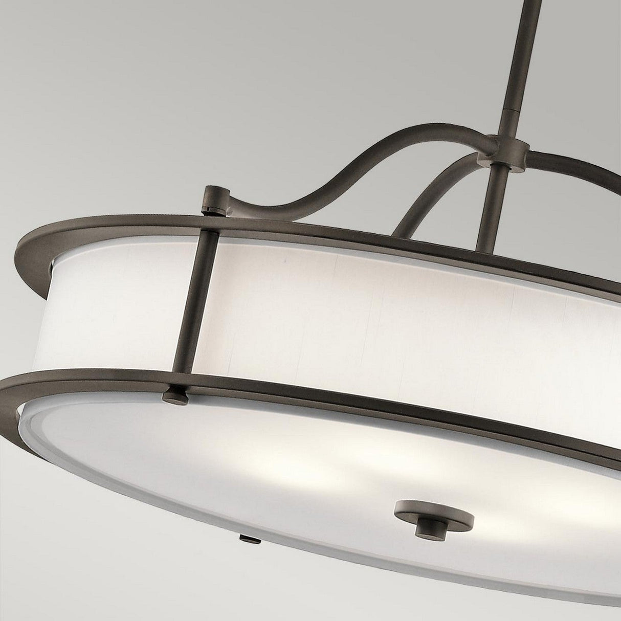 The Emory 4 Light Duo-Mount Chandelier in Olde Bronze features a contemporary design with a circular white shade framed by an Olde Bronze exterior. It is suspended from a sleek, curved metal rod against a simplistic, light gray backdrop.