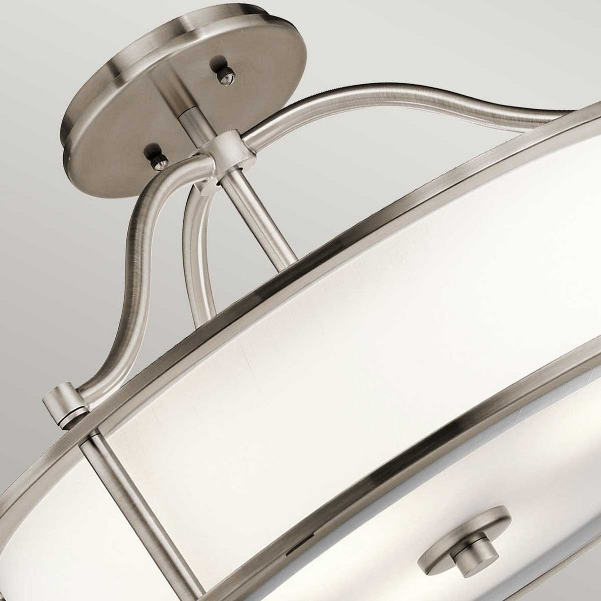 Close-up of the Emory 3 Light Duo-Mount Pendant/Semi-Flush in a circular design, featuring brushed nickel and silver finish. The contemporary style is highlighted by a translucent white cover with metal accents, mounted on the ceiling with a curved support.