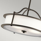The Emory 3 Light Duo-Mount Pendant/Semi-Flush in Olde Bronze showcases a circular white fabric drum shade, elegantly complemented by curved metal supports and a central stem. Set against a plain gray background, it adds sophistication to any contemporary setting.