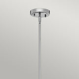 A close-up view of the Everly 1 Light Medium Pendant in chrome highlights its sleek design, similar to a contemporary pendant. Set against a plain, light gray background, this elegant fixture gracefully extends downwards from the circular ceiling mount.