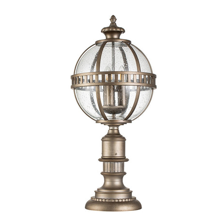 The Halleron Outdoor 3 Light Pedestal Pendant - Burnished Bronze is a Victorian Era lighting piece featuring a round glass globe, encased in burnished bronze metal bands and mounted on a decorative pedestal base. Its textured glass finish accentuates its classic and elegant charm.