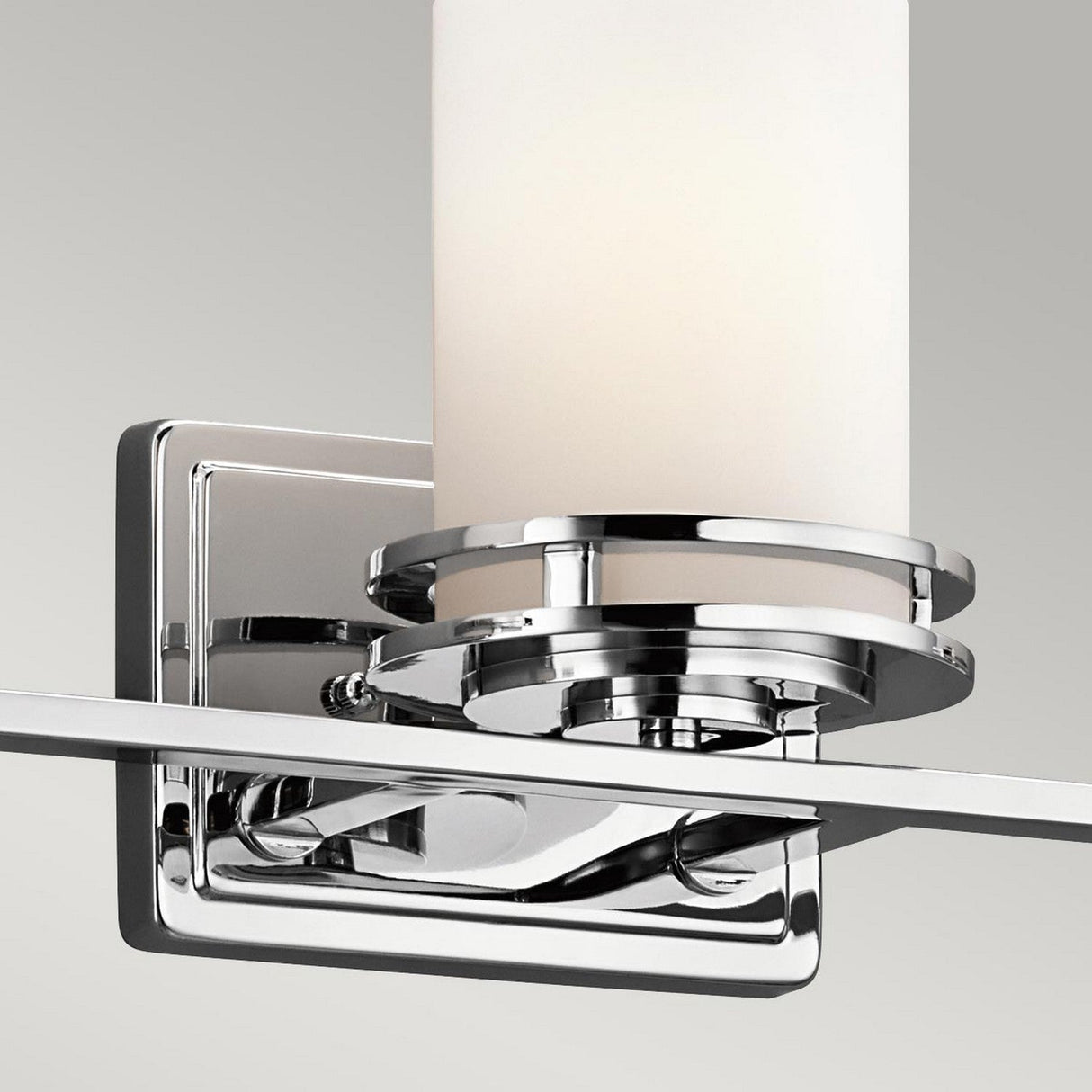 The Hendrik 3 Light Wall Light features a polished chrome finish with a cylindrical frosted glass shade, beautifully highlighted against a gray background. Its modern design is complemented by an IP44 rating, promising both style and durability.