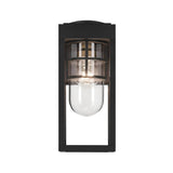 The Hone Coastal 1 Light Small Outdoor Wall Lantern in black features a clear glass bulb cover and horizontal metal accents. Shown lit against a white background, the weather-resistant fixture beautifully illuminates the glass.