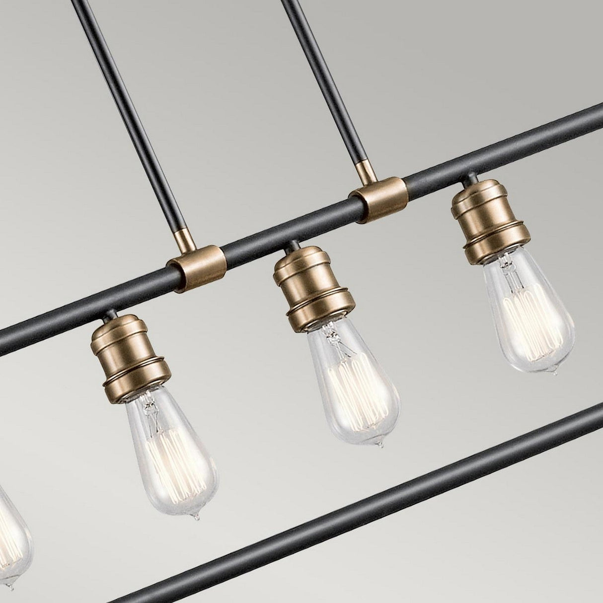 A close-up of the Imahn 5 Light Bar Pendant highlights its modern design with multiple exposed Edison-style LED bulbs. The industrial-inspired fixture showcases a sleek black metal rod complemented by natural brass accents, offering a minimalist and vintage-inspired aesthetic against a neutral backdrop.