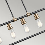 A close-up of the Imahn 5 Light Bar Pendant highlights its modern design with multiple exposed Edison-style LED bulbs. The industrial-inspired fixture showcases a sleek black metal rod complemented by natural brass accents, offering a minimalist and vintage-inspired aesthetic against a neutral backdrop.