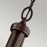 Close-up of the Lacey 4 Light Large Pendant in bronze, showcasing its elegant double-shade design with vertical metal bars and a circular attachment ring. This pendant light is suspended by a linked chain against a neutral background, adding a stylish touch to any space.
