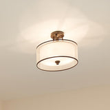 The Lacey 3 Light Small Semi Flush - Bronze showcases an elegant double-shade design with a simple white drum shape, casting a warm glow on the ceiling.