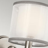 Close-up of the Lacey 1 Light Wall Light - Silver, showcasing its modern design with a classic double shade featuring white fabric wrapped around a metallic base. The light gray background accentuates the sleek aesthetic.