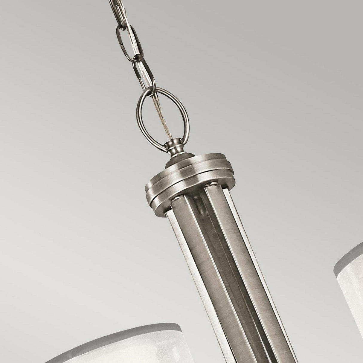 A close-up of the Lacey 5 Light Chandelier in silver showcases its modern pendant design with a brushed metal finish and a double-shade feature. This elegant lighting piece is suspended by a chain against a neutral gray background.