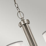 A close-up of the Lacey 5 Light Chandelier in silver showcases its modern pendant design with a brushed metal finish and a double-shade feature. This elegant lighting piece is suspended by a chain against a neutral gray background.