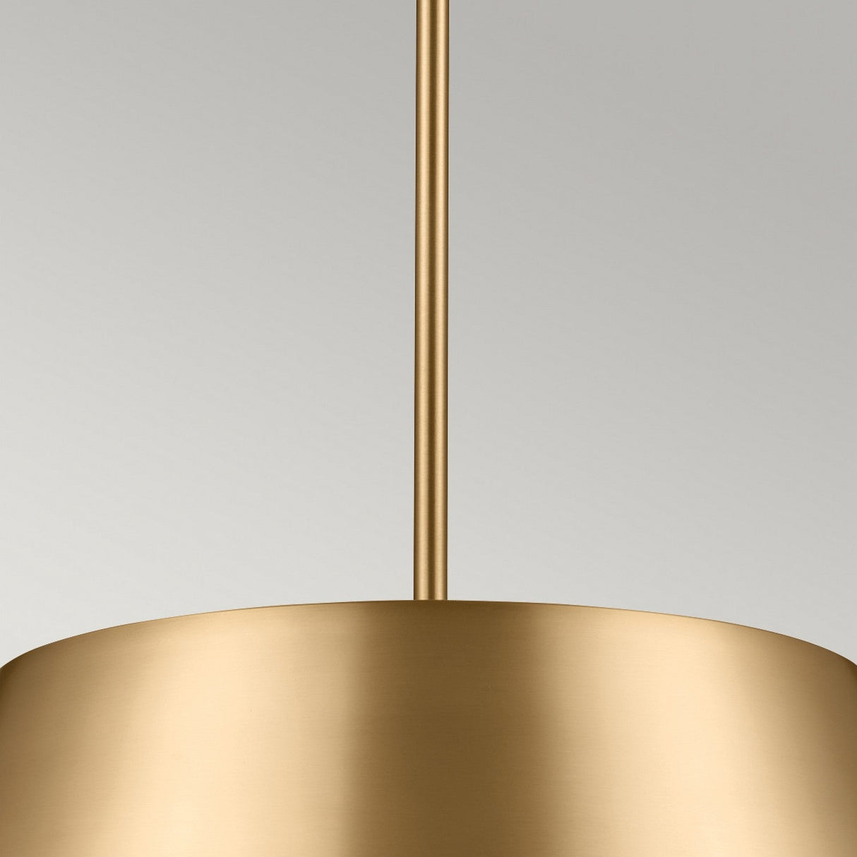 A close-up of the Luella 3 Light Duo-Mount Chandelier/Semi-Flush highlights its cylindrical design in brushed natural brass, featuring a smooth, reflective finish. This elegant lighting solution is suspended from a matching gold rod against a neutral background.