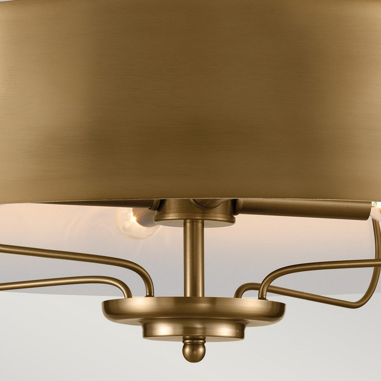 A close-up of the Luella 4 Light Duo-Mount Chandelier/Semi-Flush in brushed natural brass, showcasing its modern circular design with multiple outward-extending rods. The chandelier emits a warm glow, accentuating the smooth metallic surface against a soft, neutral background.