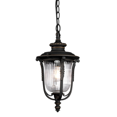 The Luverne Outdoor 1 Light Medium Chain Pendant, with its rubbed bronze finish, boasts a black metal frame adorned with decorative accents and a clear ribbed glass shade. This elegant design is ideal for brightening entryways or outdoor areas as it hangs gracefully from a chain.