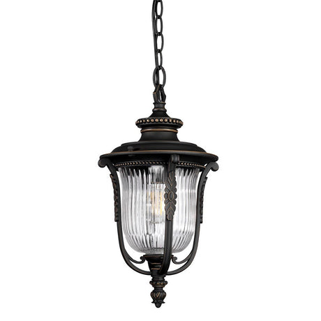 The Luverne Outdoor 1 Light Medium Chain Pendant in rubbed bronze is an elegant hanging outdoor light featuring a metal frame with intricate detailing and a clear ribbed glass shade. Its oil-rubbed bronze finish blends vintage aesthetics with modern design, ideal for enhancing exterior decor.