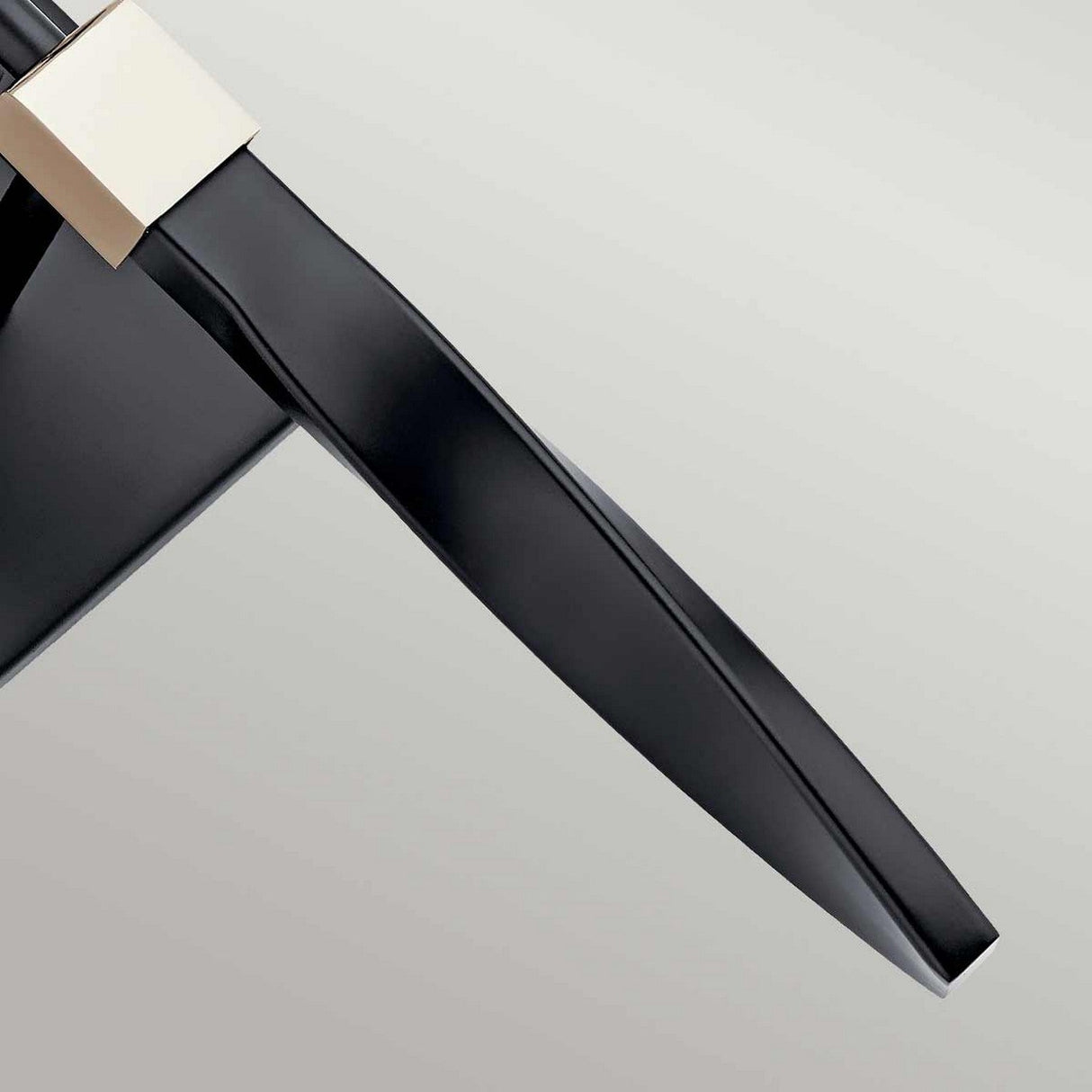 Close-up of a sleek, modern black chair with a square, metallic silver connector. The chair's backrest and seat boast smooth lines, highlighting minimalistic design aesthetics against a plain backdrop that could beautifully complement the Marette 1 Light Wall Light in Black and Nickel.