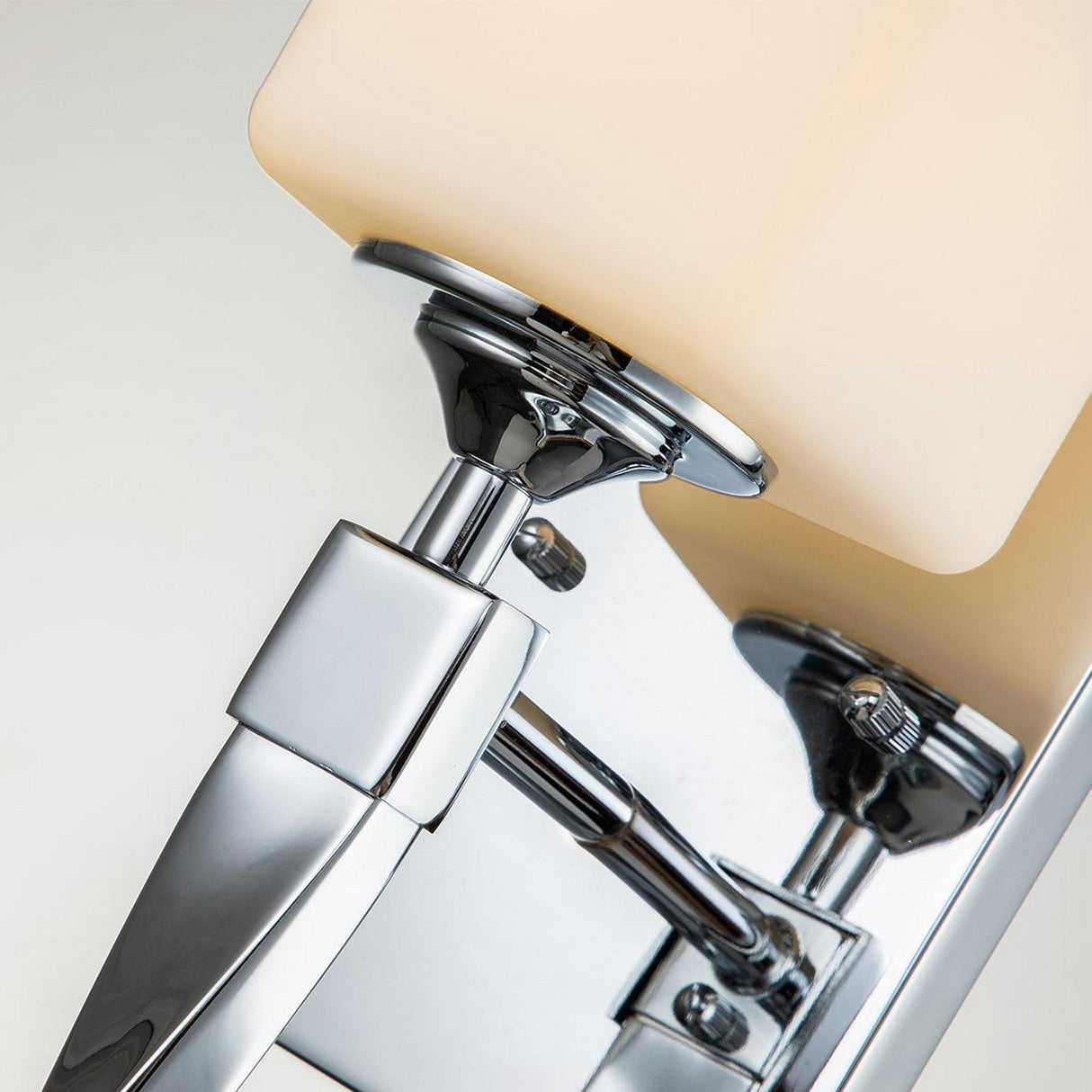 A detailed view of the Marette 1 Light Wall Light in polished chrome, featuring a cream-colored rectangular lampshade. The design highlights its sophisticated chrome surfaces and modern hardware, encapsulating the elegance of a sleek wall sconce.