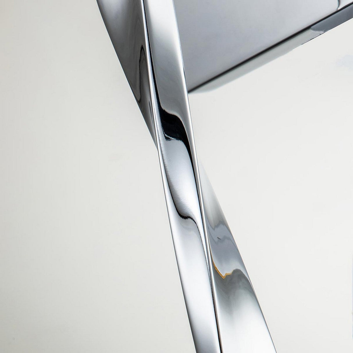A detailed view of the Marette 1 Light Wall Light in polished chrome, showcasing its sleek, twisted design with smooth, reflective surfaces set against a plain white background. The intertwined shapes produce a lively visual effect enhanced by curves and light reflections.
