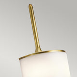 A close-up of the Mona 2 Light Large Wall Light - Natural Brass showcases its elegant white cylindrical shade and natural brass accent at the top. The sleek rod extends upwards, emitting light from energy-efficient LEDs, all set against a neutral gray background.