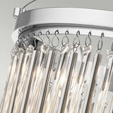 Close-up of a contemporary chandelier showcasing vertical glass rods hanging from a circular metallic frame finished in polished chrome. The illuminated rods, accompanied by delicate glass bead accents, create a radiant and sophisticated look against a light gray background similar to the Piper 3 Light Semi Flush - Polished Chrome.