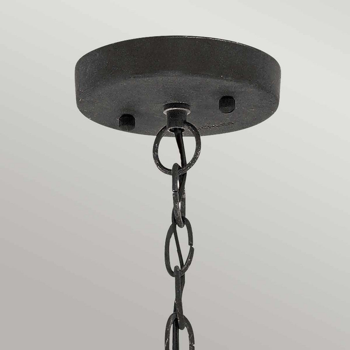 Close-up of the Riverwood Outdoor 1 Light Chain Pendant, featuring a ceiling-mounted round metal base with a weathered zinc finish. Two visible screws secure the base, and a chain resembling nautical pendant light fixtures with interlocking oval links is suspended in front of a light gray background.