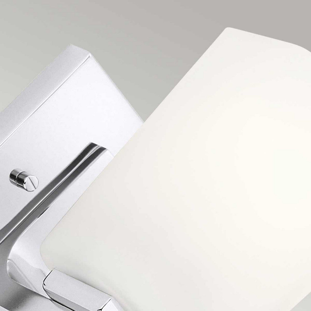 Close-up of the Roehm 1 Light Wall Light in polished chrome, featuring an opal glass shade, mounted elegantly against a light gray background. The fixture's sleek design and subtle curves convey a minimalist aesthetic while being IP44 rated for added durability.