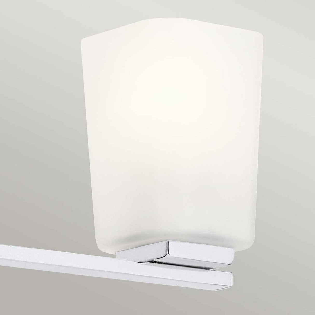 The sleek and contemporary Roehm 3 Light Wall Light - Polished Chrome showcases opal glass shades against a light gray wall, offering a minimalistic design that enhances the decor.