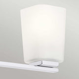 The sleek and contemporary Roehm 3 Light Wall Light - Polished Chrome showcases opal glass shades against a light gray wall, offering a minimalistic design that enhances the decor.
