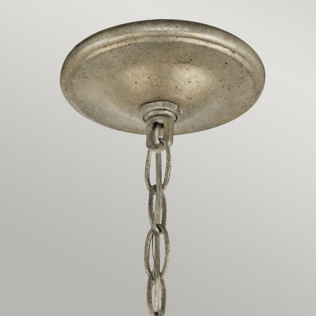 The Rosalie 5 Light Mini Chandelier in Sterling Gold is shown in a close-up view, featuring its elegant ceiling-mounted fixture with a sterling gold metallic canopy. A delicate chain cascades from its center, set against a softly lit gray background.