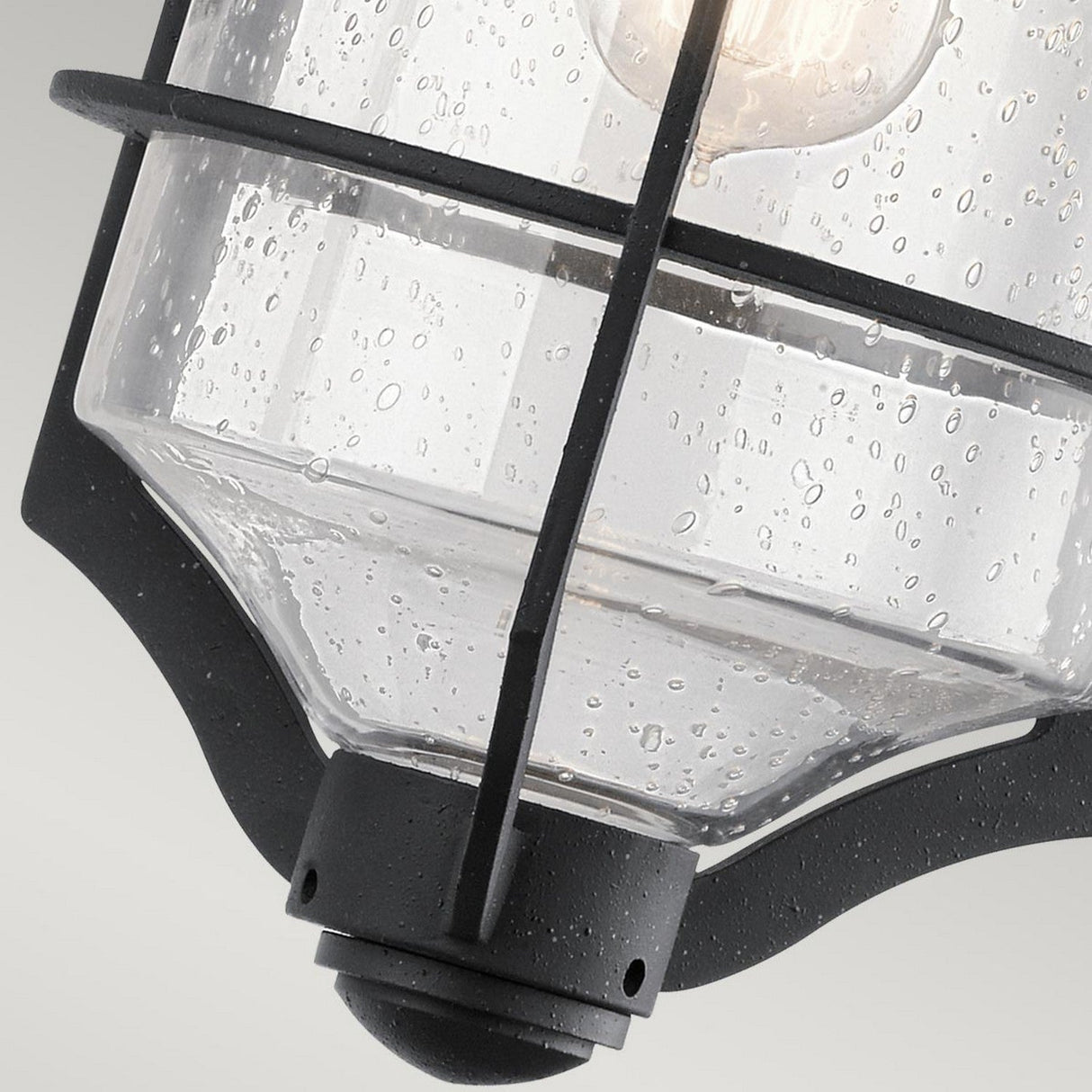 Here's a revised version of the sentence using the provided product data:

A close-up of the Royal Marine Outdoor 1 Light Medium Wall Lantern in black, featuring a vintage appeal with its metal frame and textured glass shade, which is decorated with small bubbles and droplets. Inside, a visible light bulb enhances its nautical-inspired design, making it stand out beautifully against the soft gray background—ideal for outdoor lighting.