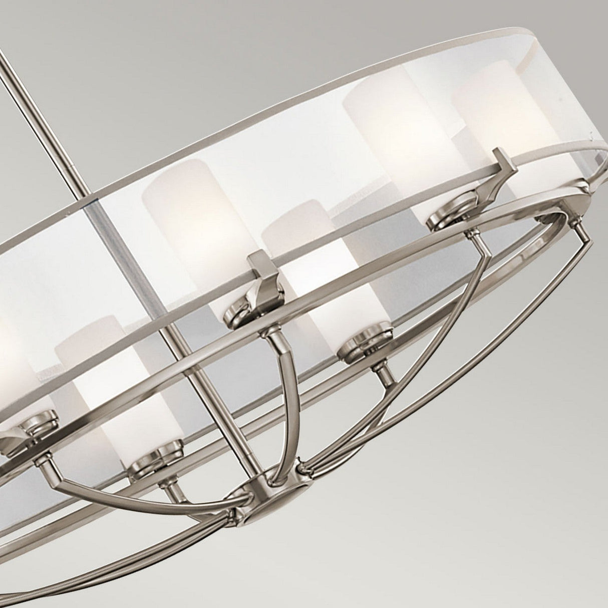 A close-up of the Saldana 8 Light Oval Chandelier - Silver reveals its modern circular frame with frosted glass shades. The sleek metal design is both contemporary and celestial-inspired, beautifully showcasing multiple light fixtures arranged in a circle.