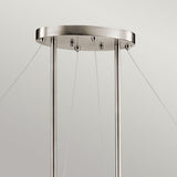 The Silver Coral 4 Light Oval Island Suspension - Silver is a brushed metal fixture showcasing a contemporary design. It features an oval ceiling mount with three vertical rods, suspended by four slender wires, and its textured metal frame enhances the minimalist style against a neutral backdrop.