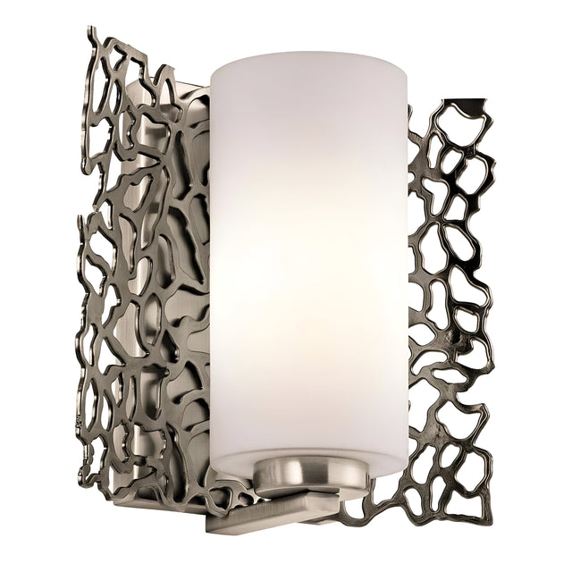 The Silver Coral 1 Light Wall Light - Silver is a contemporary wall sconce featuring a cylindrical white glass shade and an abstract patterned decorative metal backplate. The brushed metal finish offers a modern touch, while its nature-inspired aesthetic seamlessly integrates artistic elements into any space.